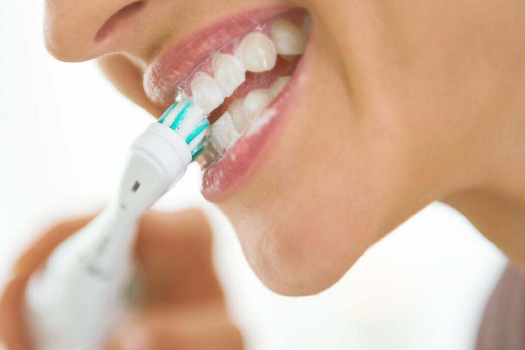 Closeup on young woman brushing teeth