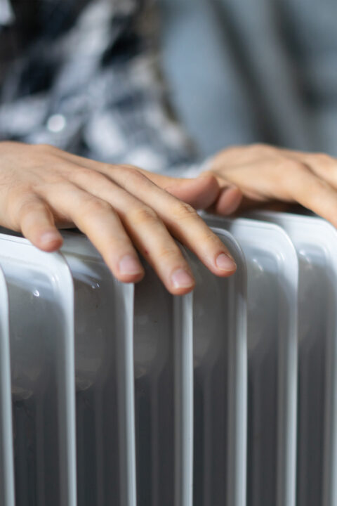 feeling cold, getting warm, hands touching heater close up