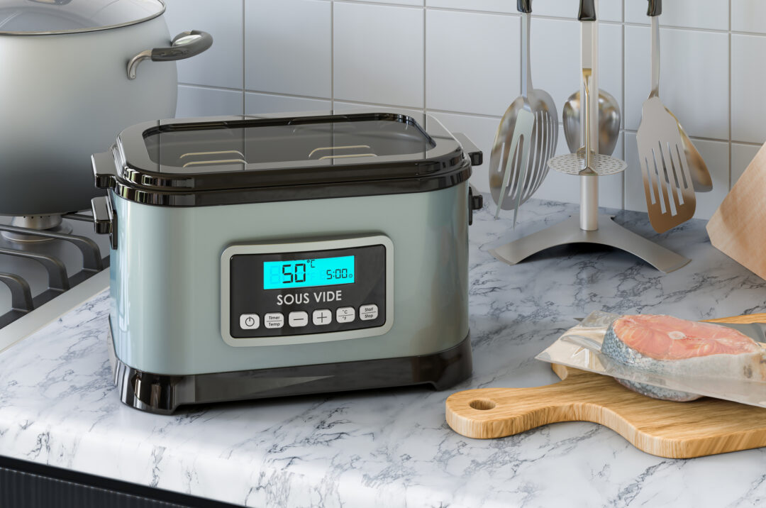 Sous vide på koekkenbordet med vakumpakket torsk paa et skaerebraet